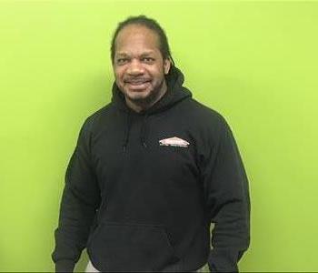 Male SERVPRO employee standing in front of green wall