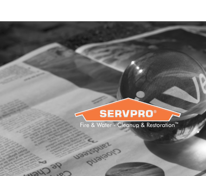 SERVPRO logo on newspaper with magnifying ball behind it