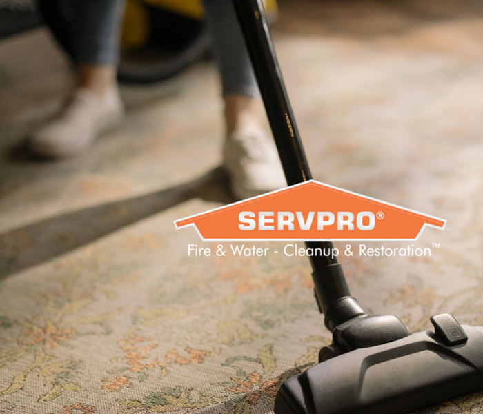 SERVPRO logo with person vacuuming in background