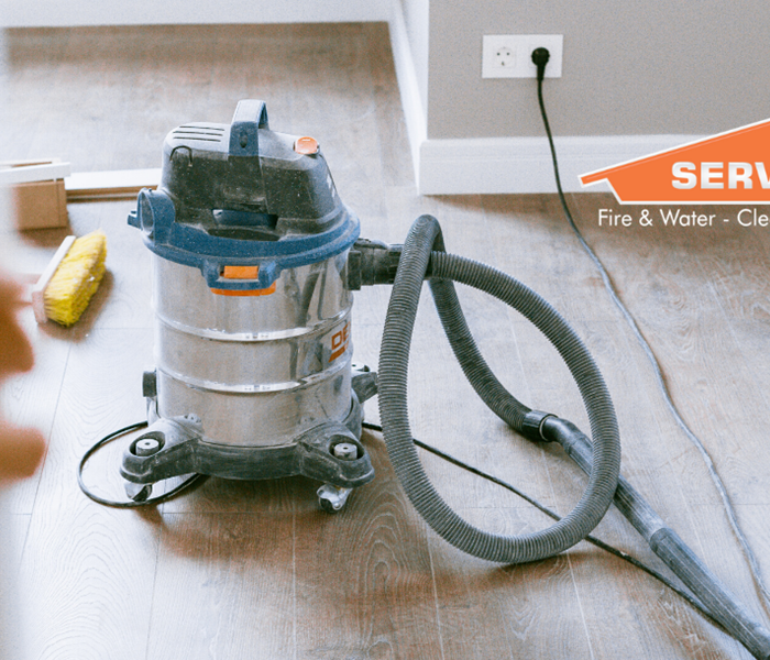 SERVPRO logo with shop vacuum and broom in background